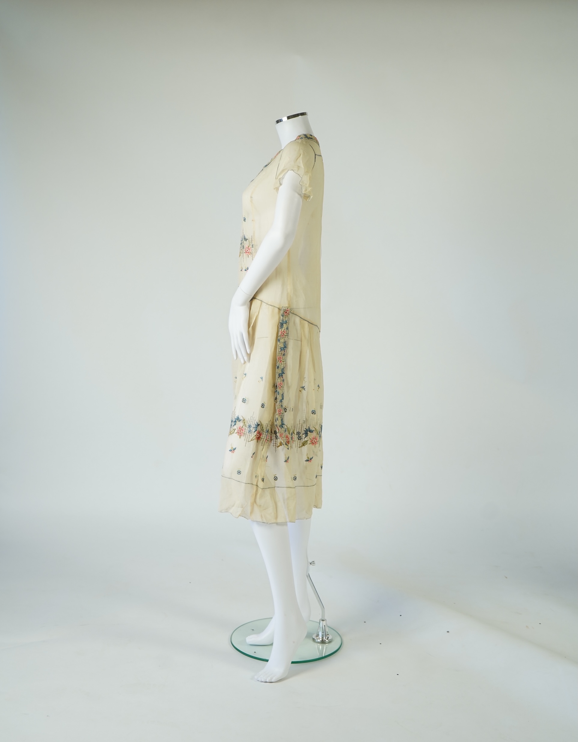 An unusual 1920's fine cream lawn summer dress with hand embroidered blue, pink, flowers, tie and picot edging., 116cm long. Condition - some small rust stains and one small tear at the back right shoulder.